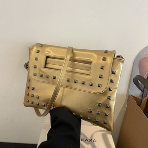 Borsa a tracolla dorata con borchie metalliche e catena in un ambiente di lusso
