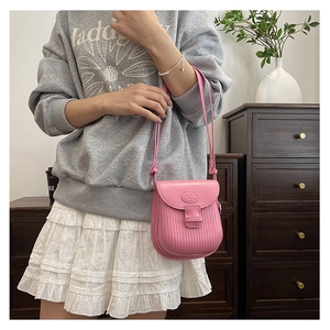 Close-up of pink pleated PU leather crossbody bag featuring a flap closure and shoulder strap