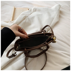 Detail view of coffee pleated bucket bag showing interior pocket and spiral wrap handle