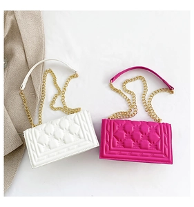 Close-up of white and rose red quilted crossbody bags with gold chain straps and square texture