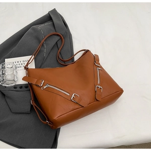 Detailed view of caramel leather tote bag featuring dual silver decorative zippers
