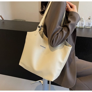 Detail showing the cream faux leather texture and elegant silver metal buckle of the tote bag