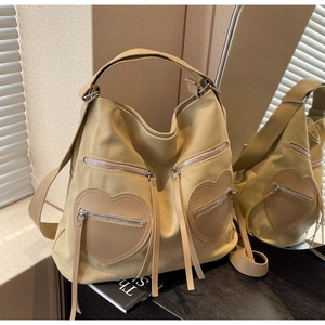 Detail of khaki corduroy tote featuring heart leather pockets and metallic zippers