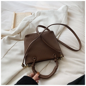 Close-up of vertical pleated texture on dark brown retro bucket bag with gold hardware