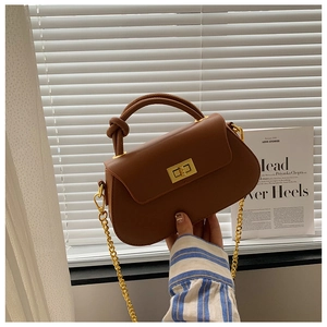 Detail of a brown leather handbag featuring a golden swivel lock and a knotted handle