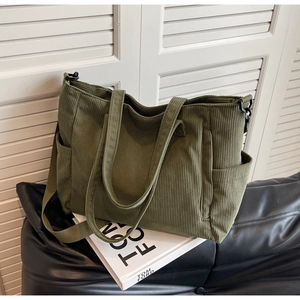 Detail of army green corduroy tote bag with side pocket and detachable strap on books