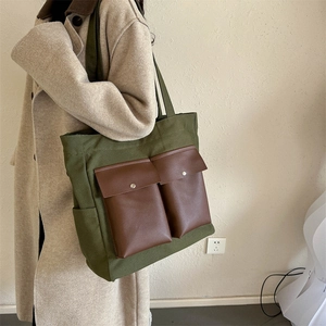 Versatile army green canvas tote bag with brown leather pockets shown on model
