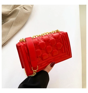 Detailed view of red quilted leather flap bag with gold chain strap and stitching
