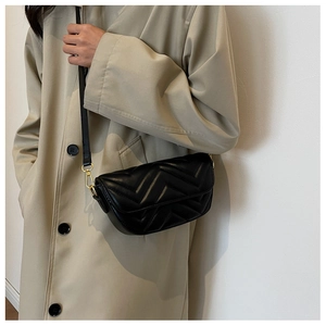 Detail of black quilted leather crossbody bag with V-pattern and gold-tone metal hardware