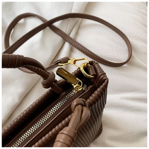 Detailed shot of vertical pleated brown leather with premium gold zipper and metal clasp