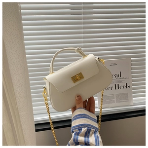 Detail view of white leather handbag with golden buckle and stylish knotted handle design