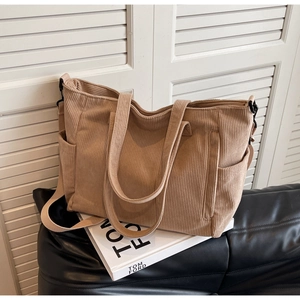 Detailed close-up of corduroy tote bag texture with side pocket and shoulder strap