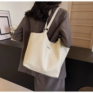 Detail view of large cream leather tote bag with fine pebble grain and metal hardware
