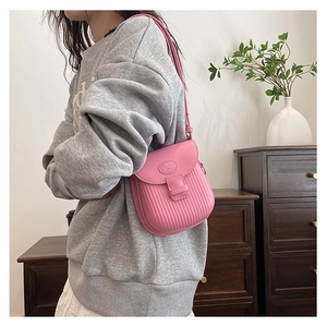 Detail of pink pleated saddle bag showing textured leather finish and adjustable strap
