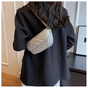 Silver-grey chevron quilted shoulder bag with gold chain strap on model's shoulder