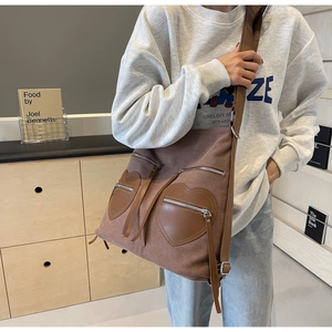 Detailed view of brown canvas bag with heart-shaped leather pockets and wide strap