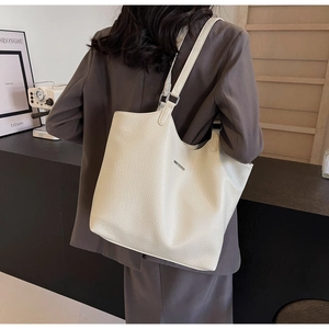 Close-up of a large beige tote bag with lychee texture and minimalist metal detail