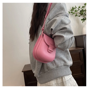 Pink saddle bag with vertical stripe embossing shown on a model for scale and style
