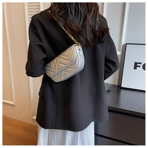 Silver chevron quilted chain shoulder bag shown on model with black suit and white dress
