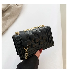 Detail view of black quilted bubble texture and gold metal chain on a crossbody bag
