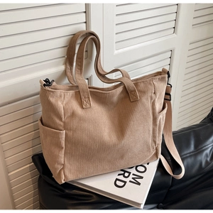 Detailed close-up of corduroy tote bag texture with side pocket and adjustable strap