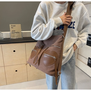 Close-up of corduroy tote bag with brown leather heart pockets and metal zipper detail