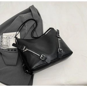 Close-up of black leather tote bag with silver zippers and buckles on grey blazer