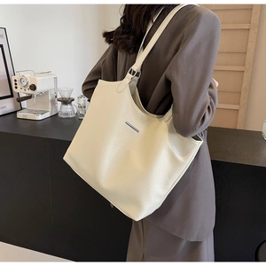 Detail of soft cream leather tote bag with lychee texture and metallic bar detail