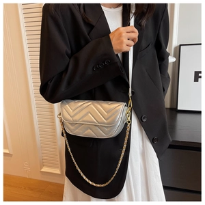 Detail of silver chevron quilted crossbody bag with gold chain strap on model
