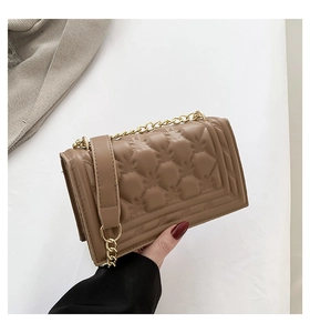 Detailed view of the diamond quilted texture and gold chain on the tan leather handbag