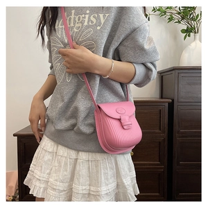Detail view of pink crossbody saddle bag with vertical embossed texture on model