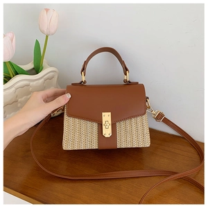 Detail einer Handtasche aus gewebtem Stroh und braunem Leder mit goldenem Metallschloss