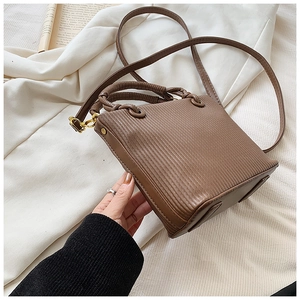 Detail view of brown pleated square handbag with glossy PU leather and gold metal hooks