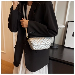 Close-up of silver quilted crossbody bag with luxury V-pattern and gold hardware details