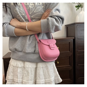 Close-up of pink mini crossbody bag with vertical striped texture and matte leather finish