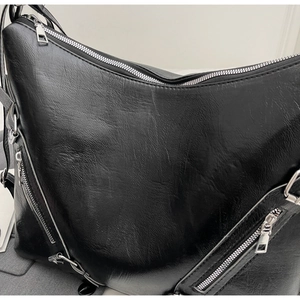 Detailed macro view of black leather tote bag with metallic silver zipper accents