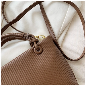 Detailed view of dark brown vertical pleated texture with golden metal buckles on bag