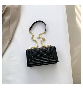 Detail of black quilted leather handbag with gold chain strap and stitching