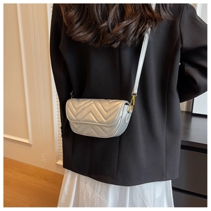 Detailed view of silver quilted crossbody bag with gold hardware on a model
