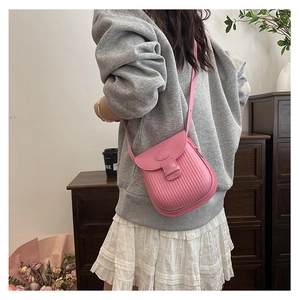 Pink textured small crossbody bag with vertical wave pattern shown on a female model
