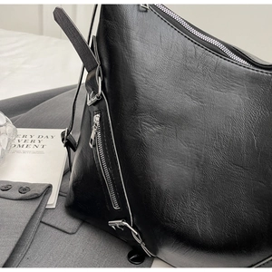 Close-up of black glossy leather tote bag with silver zipper detail and smooth texture