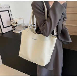 Detail of off-white lychee grain leather tote bag with minimalist silver metal bar