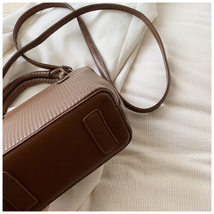 Close-up of deep brown pleated vertical texture and smooth leather finish on bucket bag