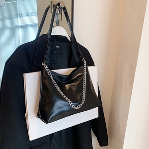Glossy black leather tote bag with silver chain strap and minimalist pleated texture