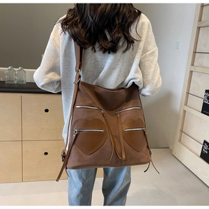 Detail of brown corduroy backpack with heart-shaped pockets and decorative long tassels