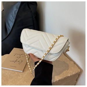 Macro view of white V-quilted texture and gold chain strap on small crossbody bag