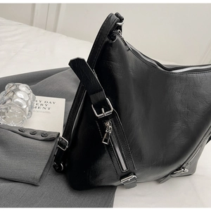Detail of black pebbled PU leather tote with silver zippers and metallic hardware decorations