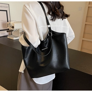 Close-up of large black leather tote bag with lychee texture and metallic detail