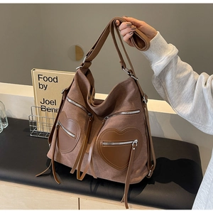 Detailed close-up of brown canvas hobo bag with unique leather heart-shaped pockets