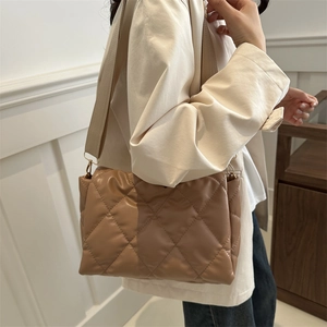 Borsa a tracolla trapuntata marrone chiaro minimalista indossata da una modella